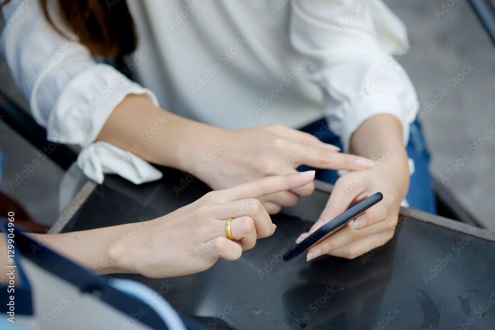Two woman looking on a smartphone and pointing at screen.