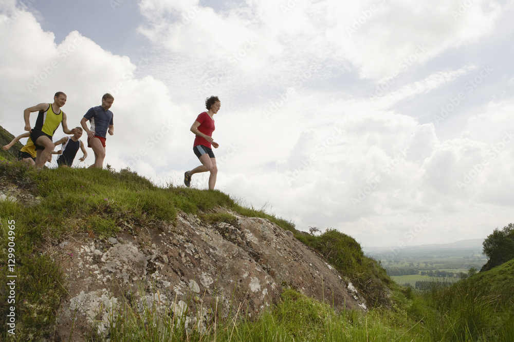 Fototapeta premium Side view of a group of people running on hill
