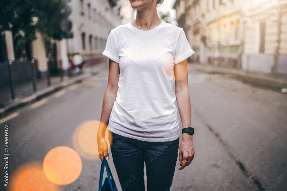 Summer day. Front view. Young woman in a white T-shirt and blue pants  standing outside. In the background, the city street. Cropped image. Bokeh  effect. Mock up. Stock Photo | Adobe Stock