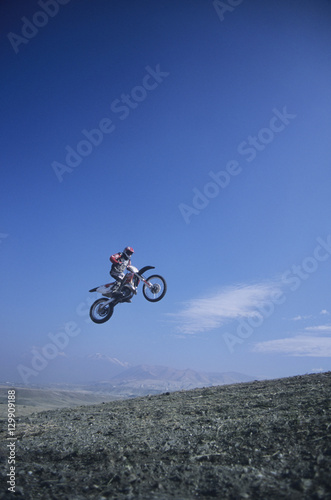 Low angle view of a man on mountain bike jumping against blue sky