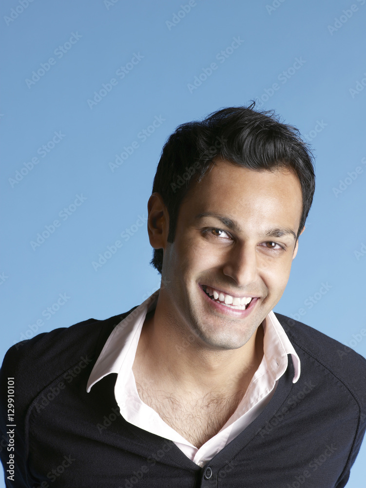 Closeup portrait of handsome young man smiling isolated on blue background Closeup portrait of handsome young man smiling isolated on blue background