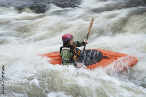 Side view of a blurred woman kayaking in rough river