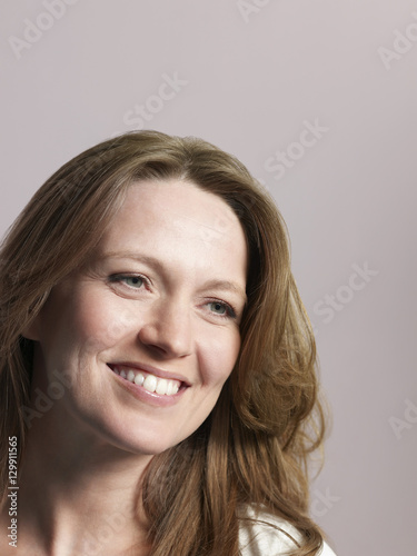 Closeup portrait of beautiful woman looking away and smiling on colored background