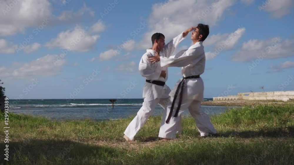 Young people, children, athletes, sport activity, combat and extreme sports, hispanic men exercising in karate and traditional martial arts. Simulation of fight on the beach near the sea Young people, children, athletes, sport activity, combat and extreme sports, hispanic men exercising in karate and traditional martial arts. Simulation of fight on the beach near the sea