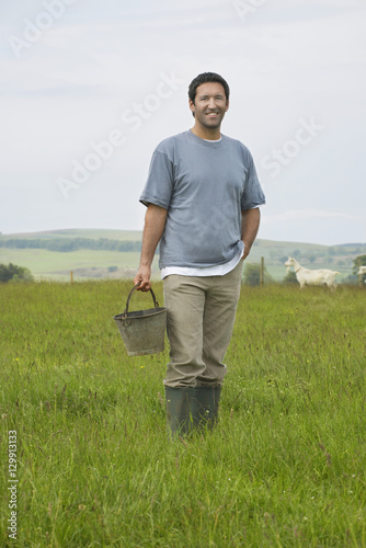 Portrait of a smiling man holding bucket in field