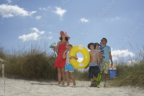 Parents with three children carrying beach accessories on a sunny day photo