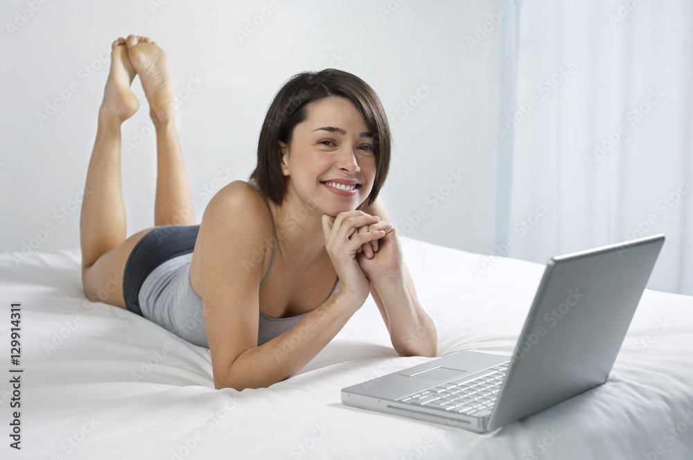 Portrait of a beautiful and relaxed young woman with laptop in bed Portrait of a beautiful and relaxed young woman with laptop in bed