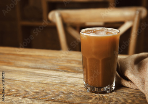 Glass of cold coffee with napkin on table