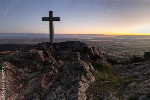 Dawn with cross in the foreground next to Sierra de Fuentes. Spain. photo