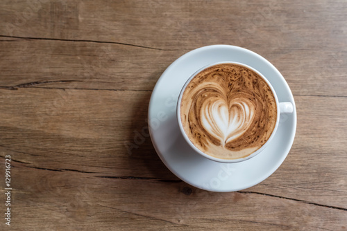 hot cappucino with latte art in heart shape on a wooden background