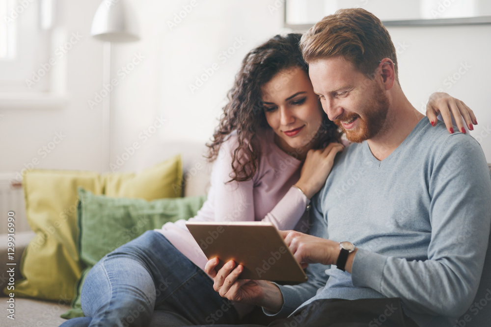 Happy couple surfing on tablet at home