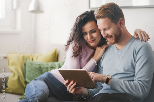 Happy couple surfing on tablet at home
