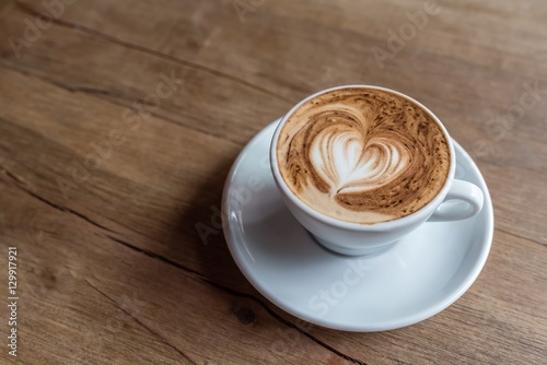 hot cappuccino with latte art in heart shape on a wooden background