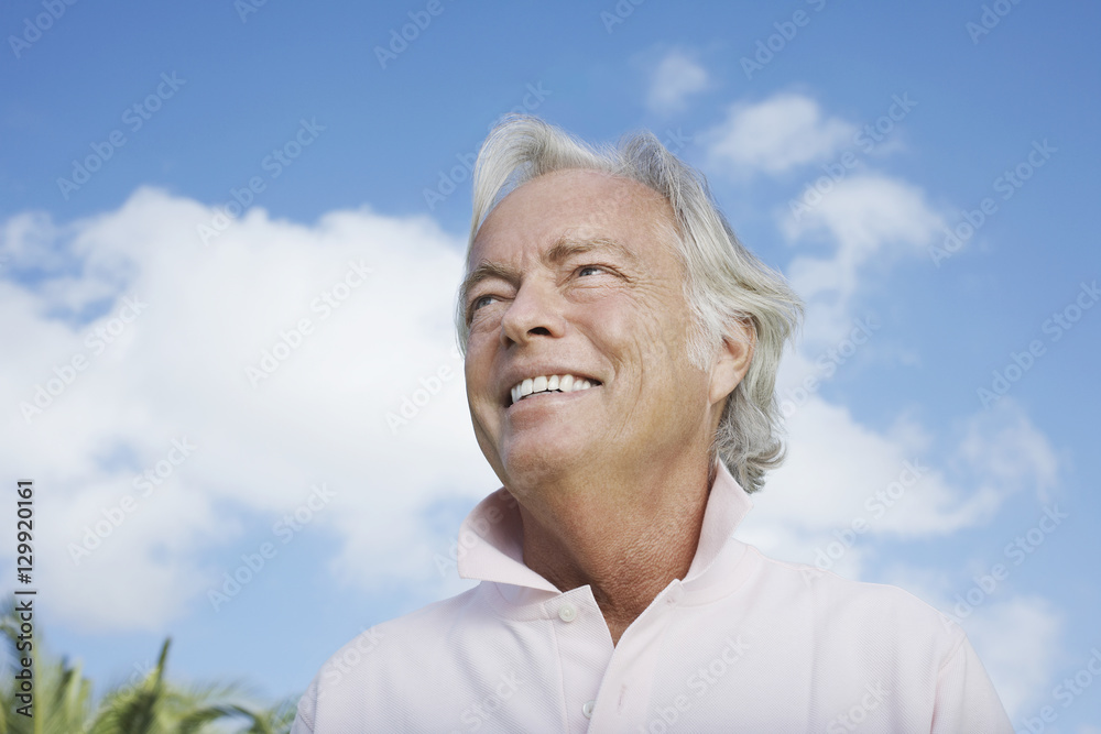 Closeup low angle view of a mature man smiling against the sky Closeup low angle view of a mature man smiling against the sky