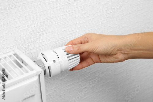 Woman holding temperature knob of heating radiator