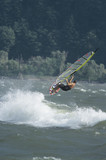 Side view of a man jumping whilst windsurfing