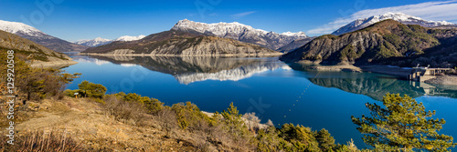 Panoramic view from hiking trail of Serre Poncon Lake in Winter with snow covered mountains. Le Rousset, Hautes Alpes, Southern French Alps, France