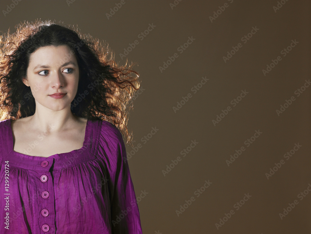 Beautiful young woman in purple dress looking sideways on colored background Beautiful young woman in purple dress looking sideways on colored background