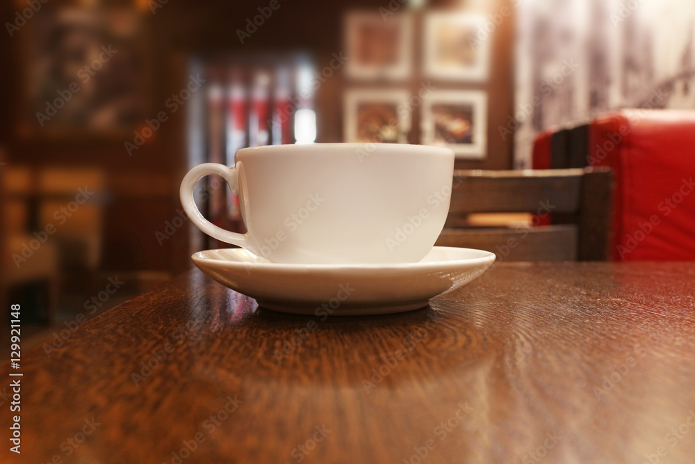 Cup with hot tasty coffee on wooden table in cafe, close up view