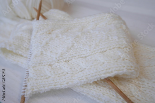 Knitting a woolen scarf with Aran pattern