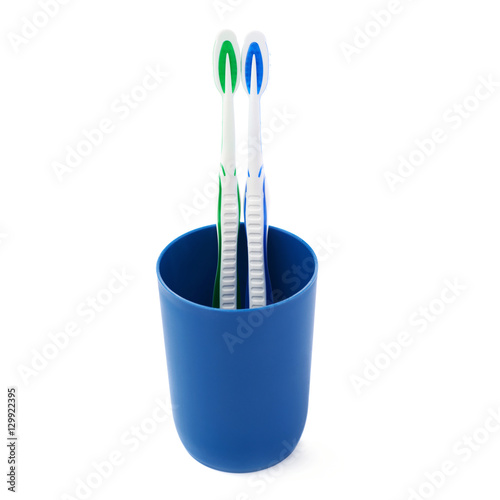 Pair of toothbrushes in blue plastic cup isolated over white background