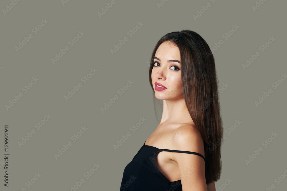 young woman standing sideways looking at the camera. Isolated gray background young woman standing sideways looking at the camera. Isolated gray background
