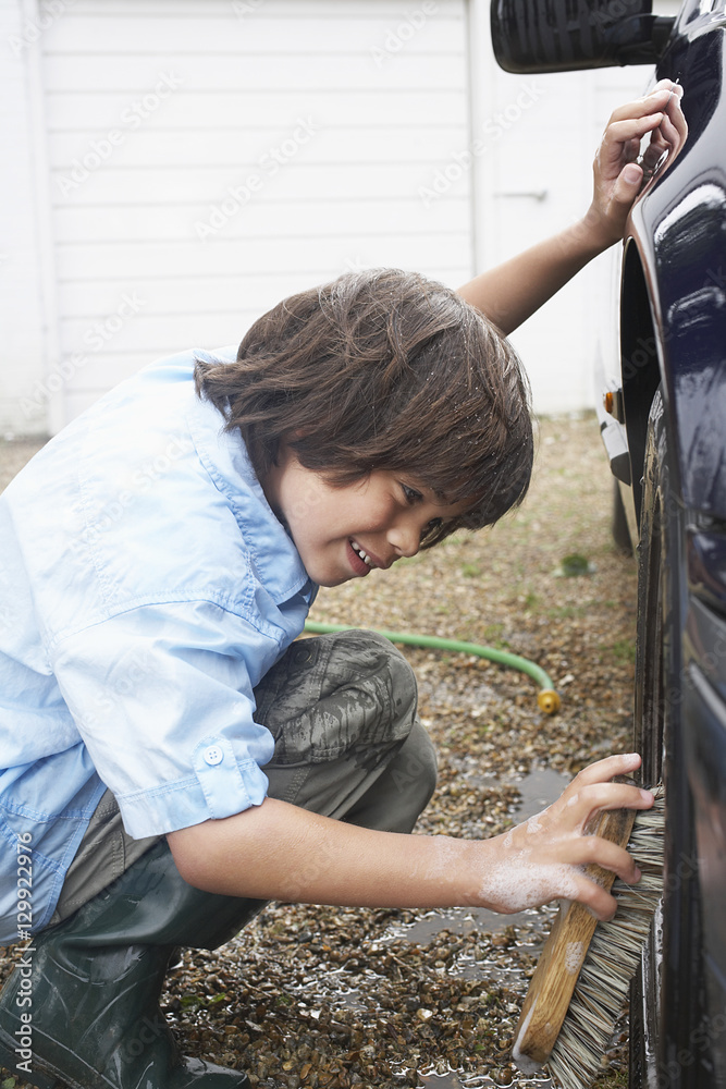 Side view of a boy washing car wheel with a brush Side view of a boy washing car wheel with a brush