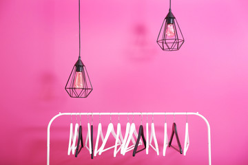 Modern hangers and light bulbs on pink wall background