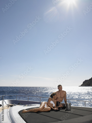Loving couple looking away while relaxing on yacht