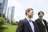 Two cheerful young businessmen laughing near office buildings