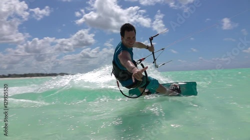 SLOW MOTION: Happy smiling kite surfer kiteboarding and showing surf shaka sign