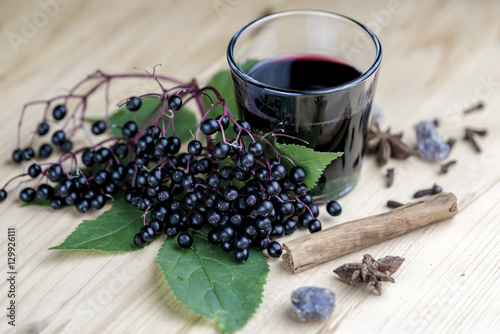 Glass of fresh elderberry syrup with ingredients