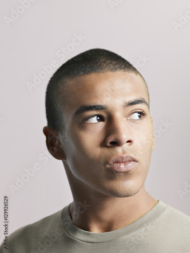 Closeup of young African American man looking away on colored background