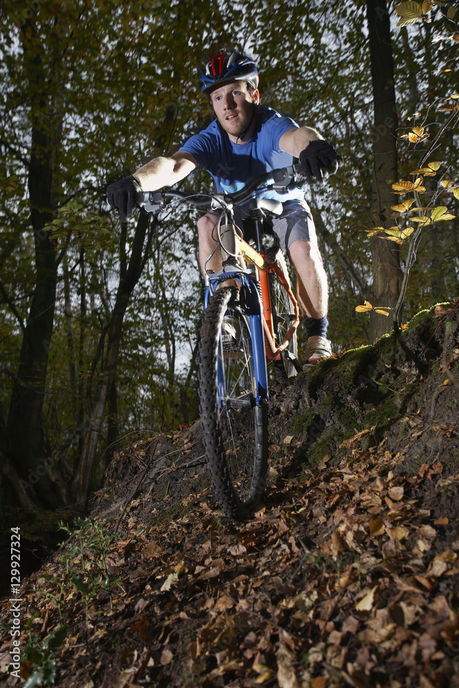 Young man riding mountain bike through forest