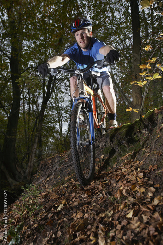 Young man riding mountain bike through forest