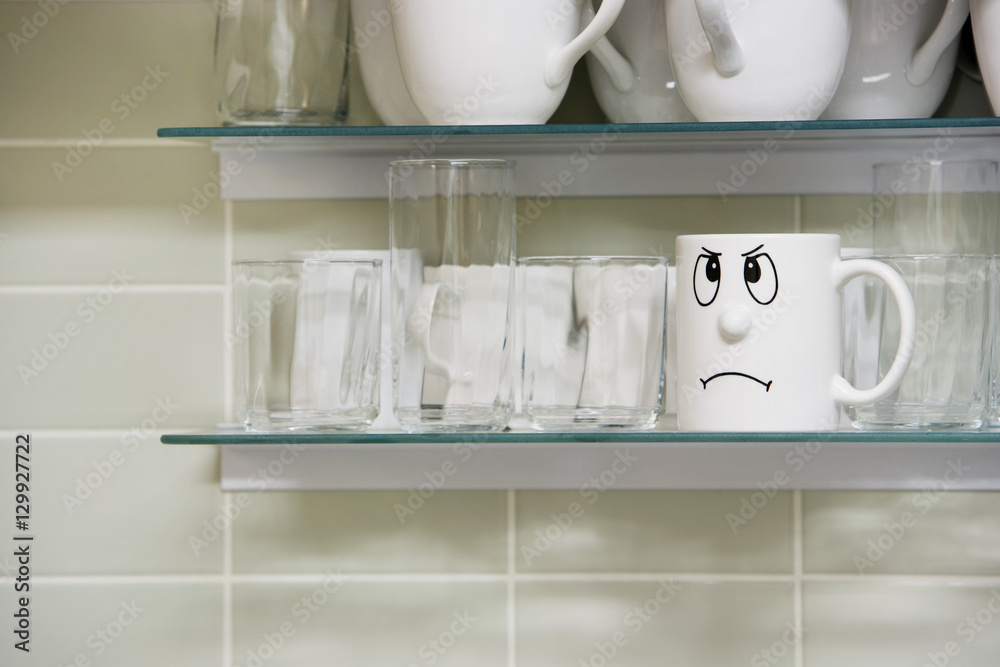 Closeup of sad face mug on kitchen shelf Closeup of sad face mug on kitchen shelf