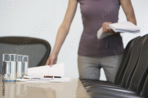Midsection of a female office worker arranging documents on conference table