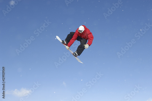 Full length of snowboard free rider making high jump against blue sky