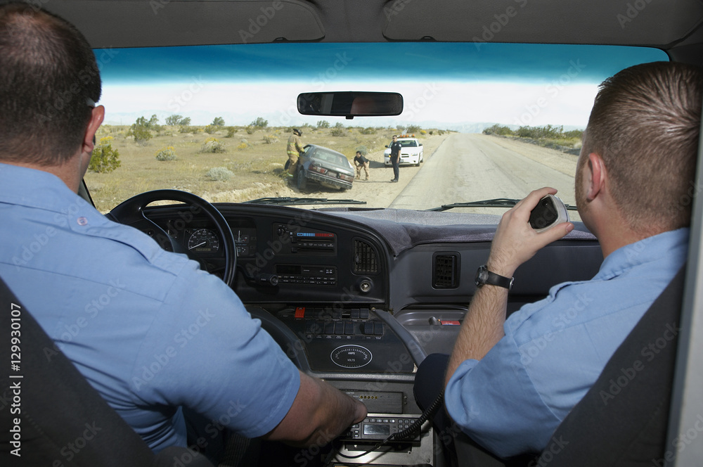 Paramedics looking through windshield at car crash scene Paramedics looking through windshield at car crash scene