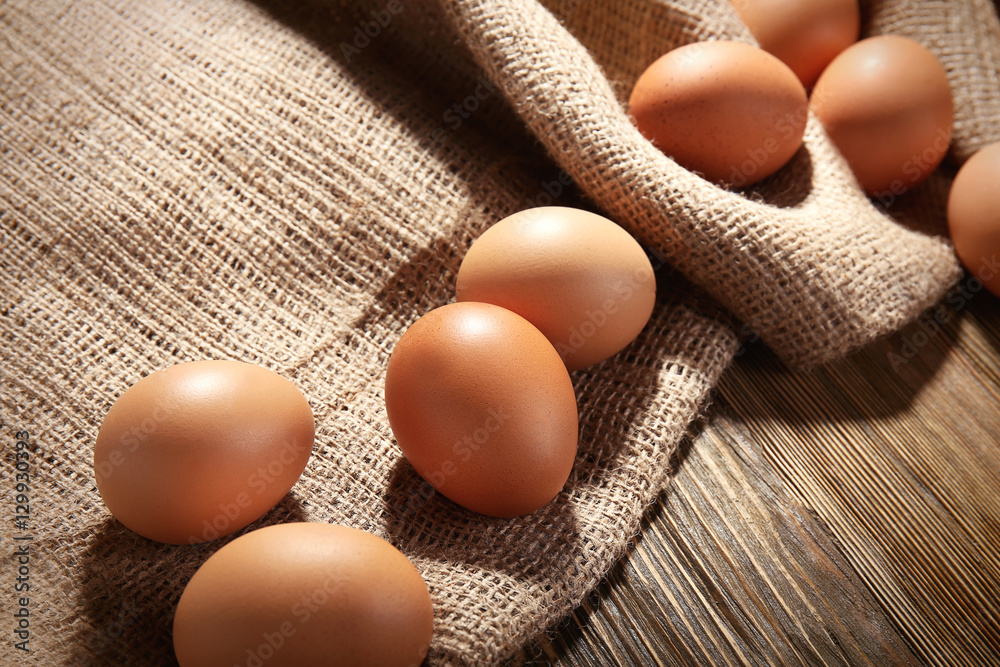 Raw eggs on sackcloth on wooden table Raw eggs on sackcloth on wooden table