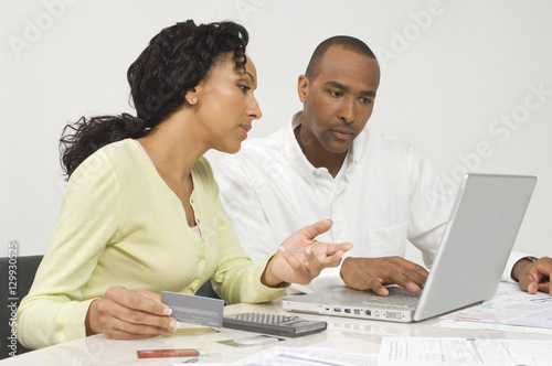 An African American couple figuring out finances on laptop