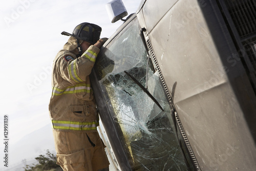 Side view of a firefighter inspecting a crashed car