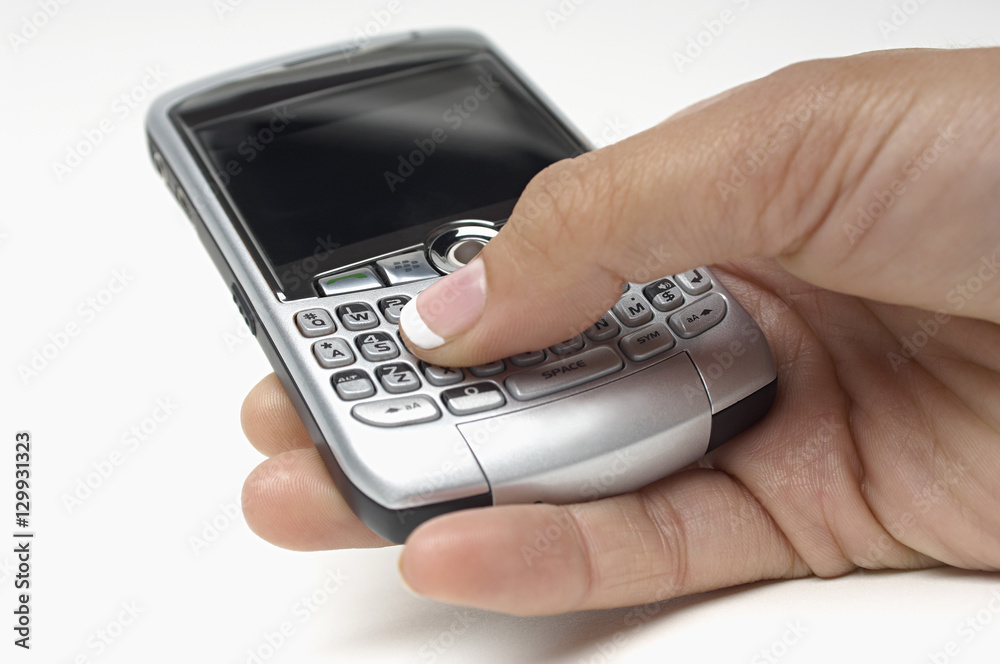 Closeup of female's hand pressing buttons on cellphone while messaging over white background Closeup of female's hand pressing buttons on cellphone while messaging over white background