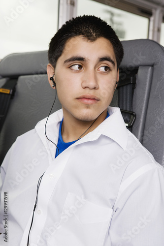 Teenage boy listening music on MP3 player in school bus photo