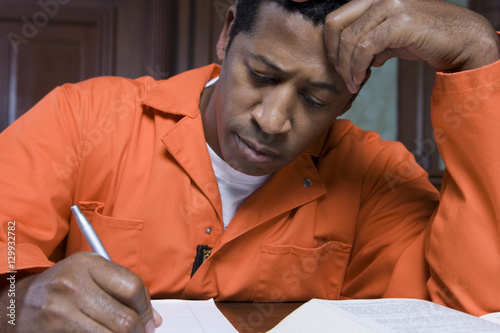 Φωτογραφία An African American male criminal writing on paper in courtroom
