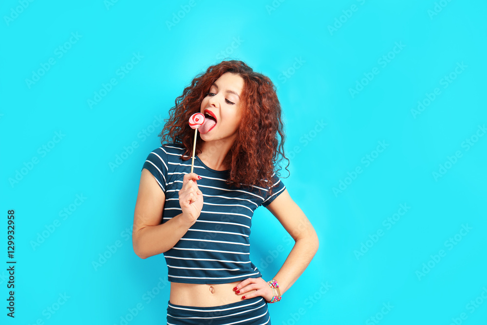 Portrait of expressive young model in striped suit with lollipop on blue background Portrait of expressive young model in striped suit with lollipop on blue background