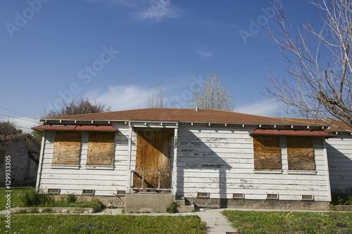 Bild auf Leinwand Lawn in front of abandoned house with boarded up windows and door