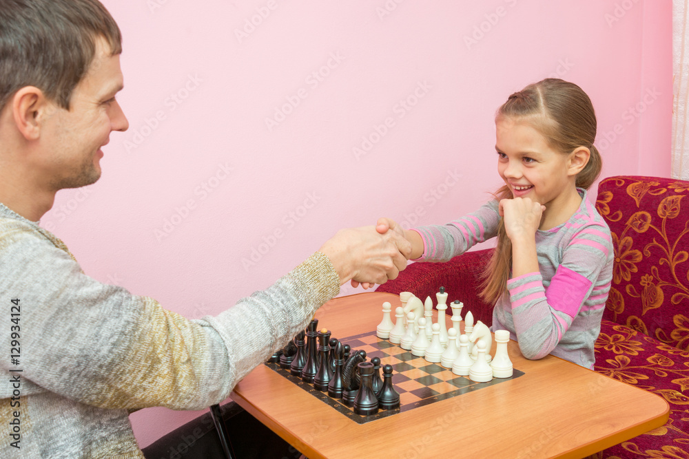 Dad and daughter greeted each other hands, about to play a game of chess Dad and daughter greeted each other hands, about to play a game of chess