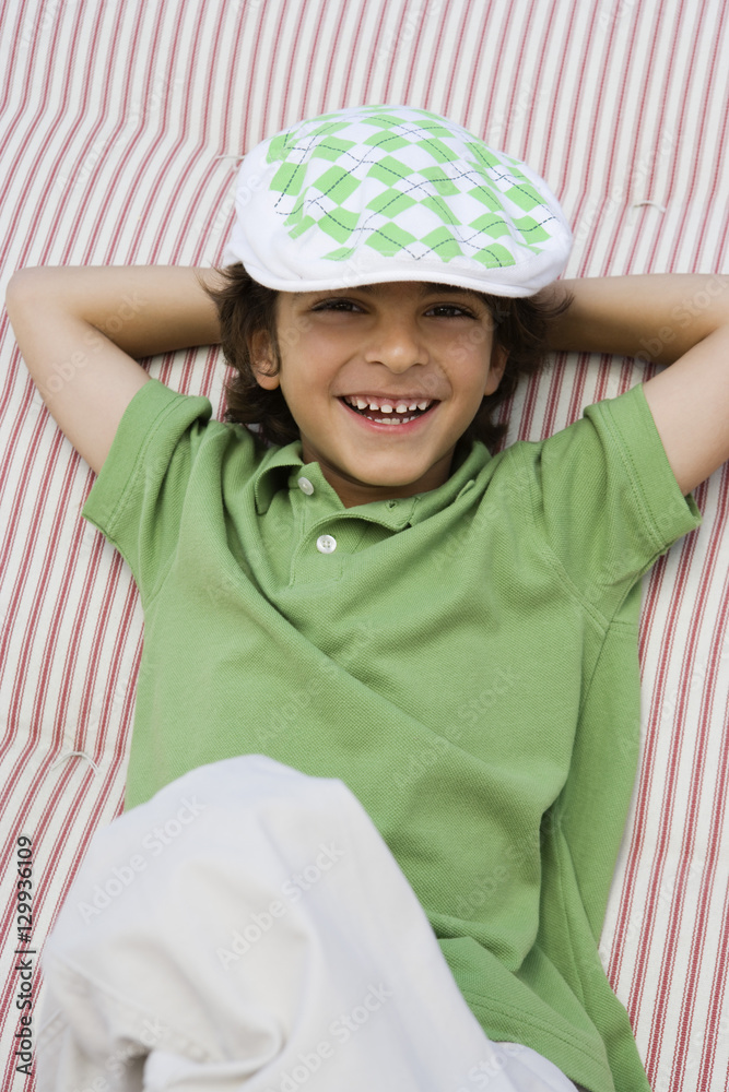 Portrait of a young boy wearing newsboy cap while relaxing on mattress Portrait of a young boy wearing newsboy cap while relaxing on mattress
