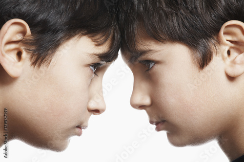 Closeup of preadolescent siblings with head to head isolated over white background